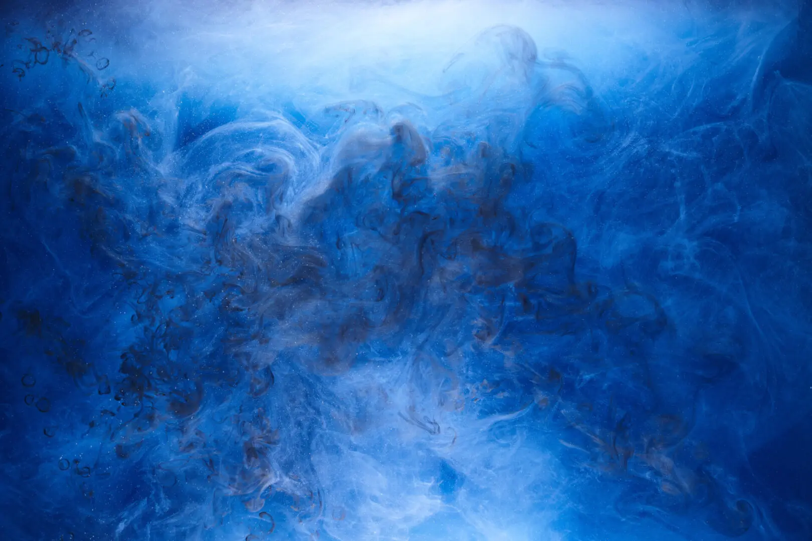 Blue smoke on black ink background, colorful fog, abstract swirling ocean sea, acrylic paint pigment underwater